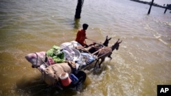 Victim of flooding from monsoon rains carries belongings salvaged from his flooded home in Sehwan, Sindh province, Pakistan, Sept. 9, 2022.