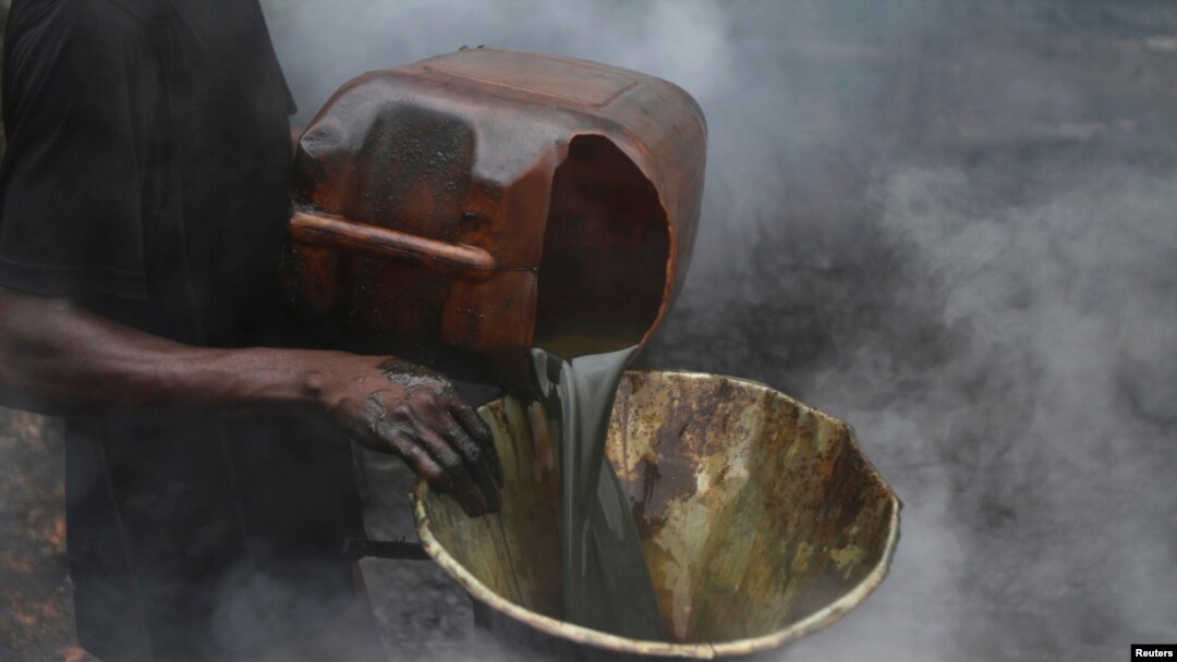 FILE - A man pours crude oil into a funnel enveloped by steam at an illegal oil refinery near the Nun River in Bayelsa state, Nigeria, Nov. 25, 2012. Nigerian National Petroleum Corporation officials said Oct. 18, 2022, that a crackdown had significantly 