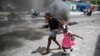 FILE - A woman guides a child past a demonstration against increasing violence in Port-au-Prince, Haiti, March 29, 2022.