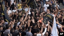 Mourners carry the body of Matin Dababa, draped in the flag of the Islamic Jihad militant group, at his funeral in the Jenin refugee camp, in occupied West Bank, Oct. 14, 2022.