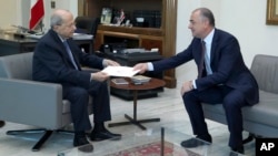 In this photo released by the Lebanese government, Lebanese President Michel Aoun, left, receives the final draft of the maritime border agreement between Lebanon and Israel from Lebanese deputy prime minister Elias Bou Saab in Beirut, Oct. 11, 2022.