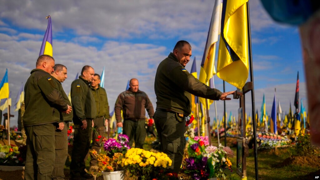Українські військові покладають квіти до могили нещодавно вбитого солдата, Харківська область, 14 жовтня 2022 року