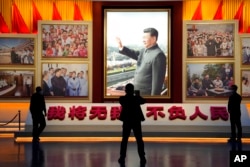 FILE - A portrait of Chinese President Xi Jinping is displayed near the words "I will put aside my own well-being for the good of my people" at the Museum of the Communist Party of China in Beijing, Oct. 12, 2022.