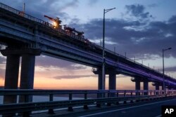 Pekerja memperbaiki bagian rel kereta api dari jembatan Krimea yang menghubungkan daratan Rusia dan Semenanjung Krimea di atas Selat Kerch, 8 Oktober 2022. (Foto: AP)