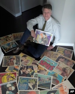 Dwight Cleveland, a major collector of movie posters and lobby cards, poses for a portrait with his first lobby card he collected for the 1929 Western movie Wolf Song. (AP Photo/Charles Rex Arbogast)