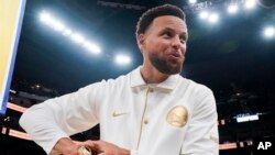Basketbole Golden State Warriors Stephen Curry reyaji apre li resevwa bag chanpyona 2021-2022 li anvan match kont Los Angeles Lakers yo nan San Francisco, Madi 18 Oktob, 2022. 