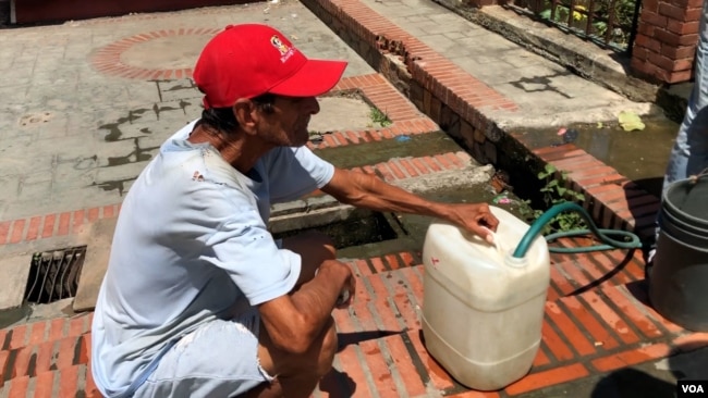 Un hombre se abastece de agua en una plaza en La Guaira, Venezuela.