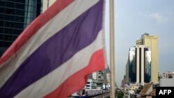 The Thai national flag flutters in the wind as a BTS commuter train rides past in Bangkok on August 24, 2022.