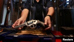 FILE - A shopkeeper shows a gun for sale in Bangkok. Thailan, a country of 69 million, had 10.3 million guns in private hands — over 4 million of them unregistered — as of 2017, the latest year for which GunPolicy.org has data.