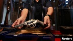 FILE - A shopkeeper shows a gun for sale in Bangkok. Thailan, a country of 69 million, had 10.3 million guns in private hands - over 4 million of them unregistered - as of 2017, the latest year for which GunPolicy.org has data.