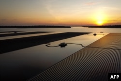 FILE - This aerial photo taken on February 22, 2022 shows floating solar panels for the Sirindhorn Dam hydro-solar farm run by the Electricity Generating Authority of Thailand (EGAT) as the sun sets in Ubon Ratchathani.