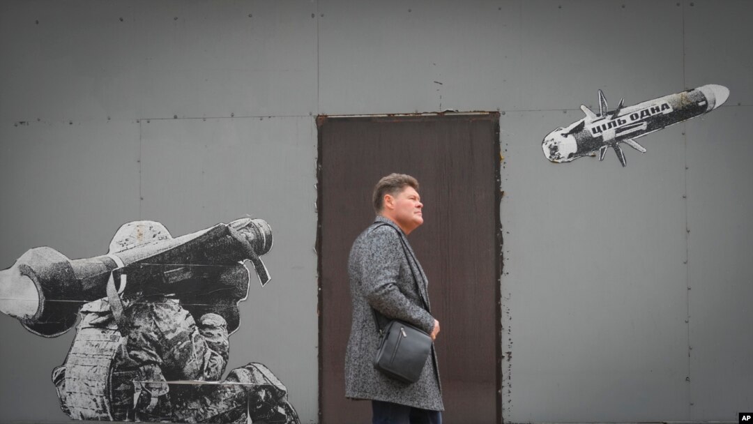Seorang pria melewati grafiti yang menggambarkan seorang tentara Ukraina tengah menembakkan rudal anti-tank di Kyiv, 24 Oktober 2022. Tulisan di rudal itu berbunyi: 'Tujuannya adalah satu.'