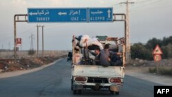 Syrians escape with their belongings north of Azaz in the country's northern Aleppo governorate, Oct. 17, 2022, as locals and others from the opposition-held cities of Azaz, Jarabulus, Mari, and al-Bab try to flee a Hay'at Tahrir al-Sham (HTS) jihadist group's advance.