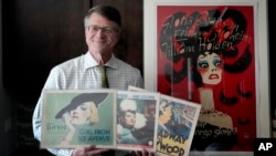 Dwight Cleveland, a major collector of movie posters and lobby cards, poses for a portrait with a three lobby card and movie poster Tuesday, Sept. 27, 2022, in Chicago. (AP Photo/Charles Rex Arbogast)
