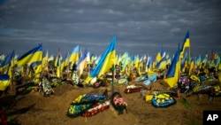 Ukrainian flags are seen in a cemetery next to graves of recently killed Ukrainian servicemen, as Ukraine marks Defenders Day, in Kharkiv, Oct. 14, 2022.