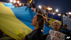 Ukrainian people who live in Greece hold a Ukrainian flag as they protest in central Athens, to condemn the Russian strikes against multiple cities across Ukraine and to mark Ukraine's Defenders Day, on Oct. 14, 2022.