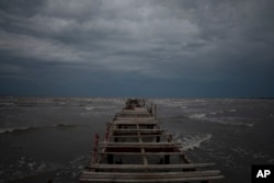 Waves kick up under a dark sky along the shore of Batabano, Cuba, Monday, Sept. 26, 2022. Hurricane Ian was growing stronger as it approached the western tip of Cuba on a track to hit the west coast of Florida as a major hurricane as early as Wednesday. (AP Photo/Ramon Espinosa)