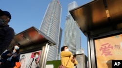 Residents wear masks wait at a bus stop in the Central Business District in Beijing, Oct. 24, 2022. China's economic growth picked up in the latest quarter but still was among the weakest in decades as the ruling Communist Party tries to reverse a slump.