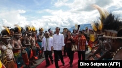 Presiden Joko Widodo (tengah) dan Ibu Negara Iriana Widodo (tengah, kedua dari kanan) tiba di Jayapura, Papua, dalam kunjungannya pada 27 Desember 2014. (Foto: AFP/Rusman/Presidential Palace)