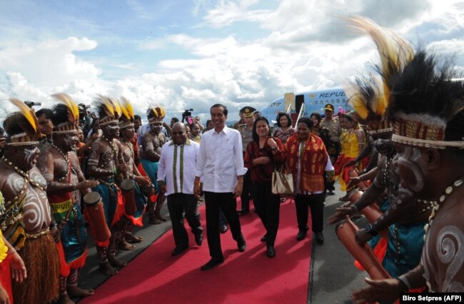 Presiden Joko Widodo (tengah) dan Ibu Negara Iriana (tengah ke-2 dari kanan) tiba di Jayapura, Papua, disambut oleh Gubernur Papua Lukas Enembe (kiri) dan istrinya Yewuce (kanan). (Foto: AFP)