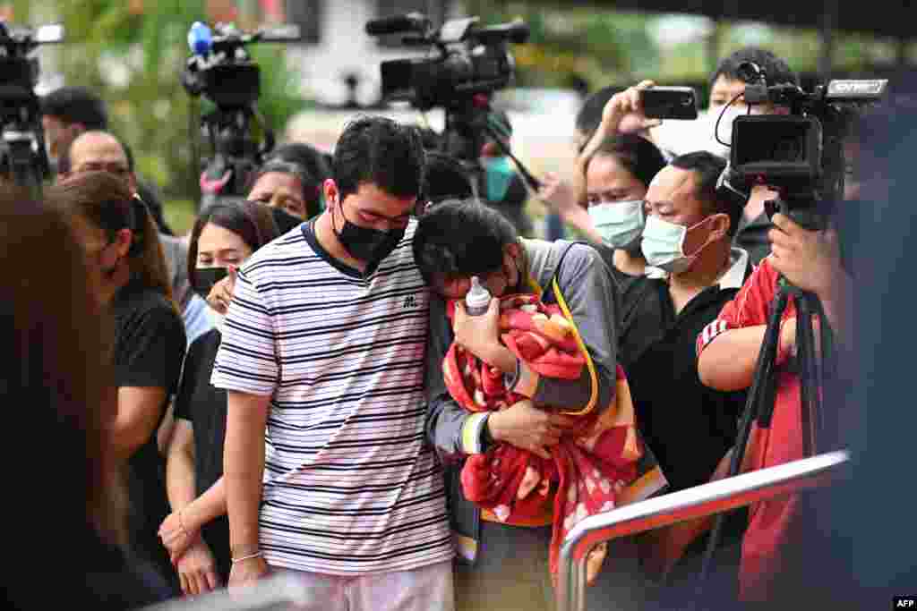 Sittipong Taothawong, left, comforts his wife Kanjana Buakumchan as she holds their child&#39;s milk bottle and blanket while standing outside the nursery in Na Klang in Thailand&#39;s northeastern Nong Bua Lam Phu province, the day after a former police officer killed at least 37 people in a mass shooting at the site.