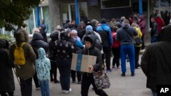 Una mujer lleva una caja mientras se distribuye ayuda humanitaria en la aldea de Mykhailo Lukasheve, en la región de Zaporizhzhia, Ucrania, el 20 de octubre de 2022.