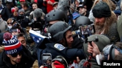 FILE - Pro-Trump protesters clash with DC police officer Michael Fanone at a rally to contest the certification of the 2020 US presidential election results at the U.S. Capitol Building, Jan. 6, 2021.