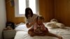 FILE - Ukrainian refugee Tatyana Bogkova brushes her daughter Eva's hair in the flat they share with other Ukrainian refugees in Madrid, Spain, Sept. 17, 2022. Bogkova, who left with her daughter and mother upon Russia's invasion of Ukraine, is struggling to find a job in Spain. 