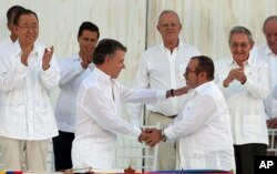 ARCHIVO - En esta foto de archivo de septiembre de 2016, el presidente de Colombia, Juan Manuel Santos, y el comandante de las Fuerzas Armadas Revolucionarias de Colombia, FARC, Rodrigo Londoño, se se saludan en el marco de la firma del acuerdo de Paz en La Habana, Cuba.