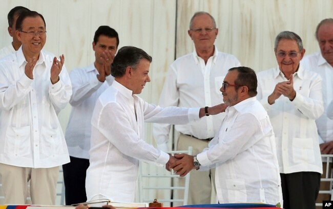 ARCHIVO - En esta foto de archivo de septiembre de 2016, el presidente de Colombia, Juan Manuel Santos, y el comandante de las Fuerzas Armadas Revolucionarias de Colombia, FARC, Rodrigo Londoño, se se saludan en el marco de la firma del acuerdo de Paz en La Habana, Cuba.