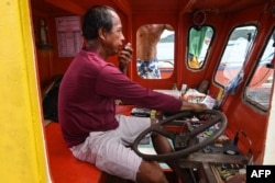 In this photo taken on August 11, 2022, fisherman Christopher de Vera talks over a two-way radio with fellow fishermen inside their fishing "mother" boat in the village of Cato, Infanta town, Pangasinan province, as they prepare to leave for a fishing expedition to the South China Sea.