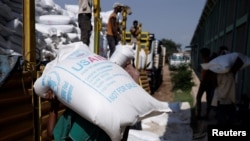 FILE - Laborers offload bags of grains as part of relief food that was sent from Ukraine at the World Food Program (WFP) warehouse in Adama town, Ethiopia, on Sept. 8, 2022.