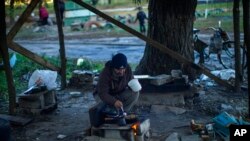 FILE - A man cooks on a makeshift stove in Kivsharivka, Ukraine, Oct. 16, 2022. Residents in Kivsharivka have been living with no gas, electricity or running water for around three weeks.