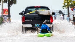 A truck pulls a man on a kayak on a low-lying road after flooding in the aftermath of Hurricane Ian, in Key West, Florida, Sept. 28, 2022. 