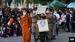 Police carry a coffin containing a victim in the day care center attack for cremation at Wat Rat Samakee temple in Uthai Sawan, northeastern Thailand, Tuesday, Oct. 11, 2022.