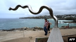 Visitors look at the sculpture 'Flooded Weir' by Vlase Nikoleski on display between Bondi and Tamarama beach as part of the Sculpture by the Sea exhibition in Sydney on Oct.21, 2022. 