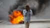 FILE - A man walks past a burning barricade during a protest over the death of journalist Romelo Vilsaint, in Port-au-Prince, Haiti, Oct. 30, 2022. As violence sweeps Haiti, the country's journalists are being targeted. 