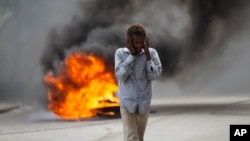 FILE - A man walks past a burning barricade during a protest over the death of journalist Romelo Vilsaint, in Port-au-Prince, Haiti, Oct. 30, 2022. As violence sweeps Haiti, the country's journalists are being targeted. 