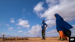 Fartum Issack, right, and her husband, Adan, stand by the grave of their 1-year-old daughter at a displacement camp on the outskirts of Dollow, Somalia, Sept. 19, 2022.