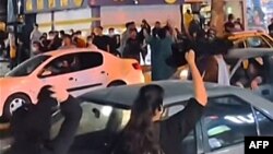 This grab taken from a UGC video of anonymous source shows Iranian women cheering and waving their hijab (headscarf) above their heads in a street in Sanandaj, the capital of Iran's Kurdistan province, Sept. 26, 2022.