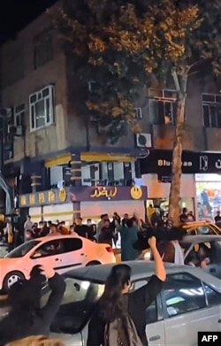 This grab taken from a UGC video of anonymous source shows Iranian women cheering and waving their hijab (headscarf) above their heads in a street in Sanandaj, the capital of Iran's Kurdistan province, on Sept. 26, 2022.