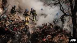 Ukrainian firefighters work on a destroyed building after a drone attack in Kyiv on Oct. 17, 2022.
