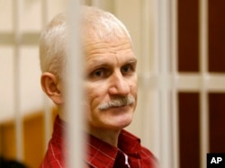 FILE - Ales Bialiatski, the head of Belarusian Vyasna rights group, stands in a defendants' cage during a court session in Minsk, Belarus, on Nov. 2, 2011.