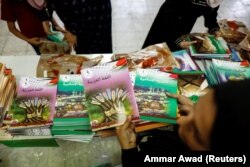 Seorang perempuan membagikan buku pelajaran yang belum diedit sebagai bagian dari protes orang tua Palestina karena Israel dianggap telah menyensor buku pelajaran sekolah di kamp pengungsi Shuafat di Yerusalem Timur. (Foto: Reuters)