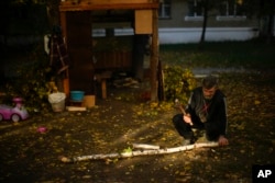 A local man cuts pieces of firewood in Kivsharivka, Ukraine, Sunday, Oct. 16, 2022. (AP Photo/Francisco Seco)