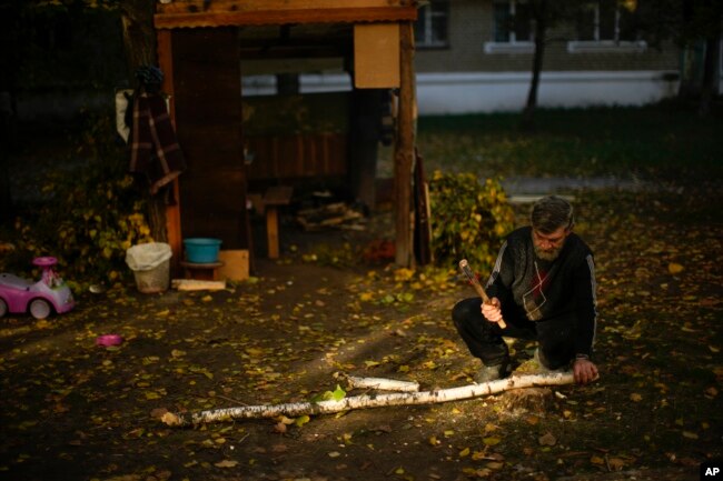 A local man cuts pieces of firewood in Kivsharivka, Ukraine, Sunday, Oct. 16, 2022. (AP Photo/Francisco Seco)