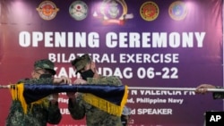 Philippine and US military officers unfurl a flag during opening ceremonies of joint exercises in Taguig city, Philippines, Oct. 3, 2022. The drills practiced responses to a crisis in a region long on edge over South China Sea disputes and China's hostile