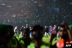 Para suporter terlihat turun ke lapangan setelah pertandingan sepak bola antara Arema FC dan Persebaya di stadion Kanjuruhan di Malang, Jawa Timur. (Foto: AFP)