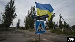 Ukrajinska zastava vijori se na raskrsnici u upravo oslobođenom selu Visokopilja, na fotografiji napravljenoj 27. septembra 2022.