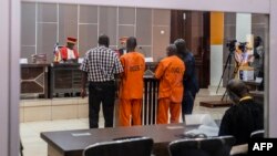 Ousman Yaouba (C-R) and Issa Salet Adoum (C-L), co-accused with one other perpetrator of the massacre of 46 villagers in May 2019, stand iuring the verdict of an historical and a long-awaited trial in the Special Criminal Court in Bangui on October 31, 2022.